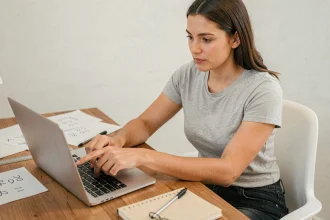 Femme utilisant un convertisseur pieds en centimètres sur un ordinateur portable dans un bureau à domicile
